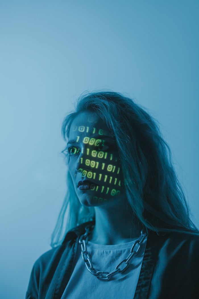 About Stylized portrait of a woman with binary code projected on her face, evoking themes of technology and identity.